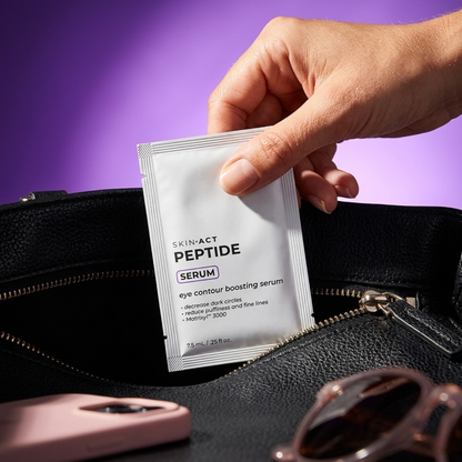 Hand holding a Skin-Act Peptide Serum packet over a black handbag with sunglasses on a purple background